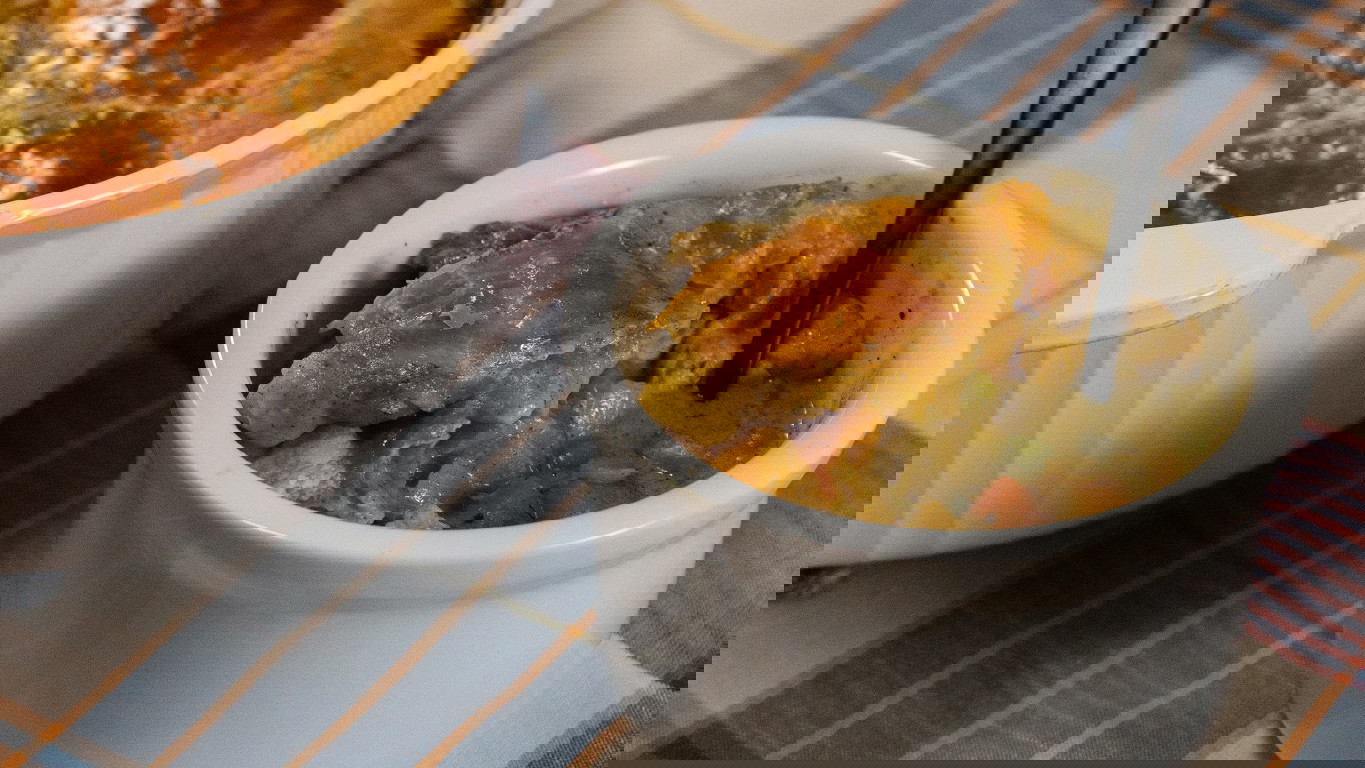 A white ramekin filled with creamy chicken pot pie, made with tender chinks of halal chicken and a hearty blend of peas, carrots, celery, and onion in a seasoned homemade gravy.