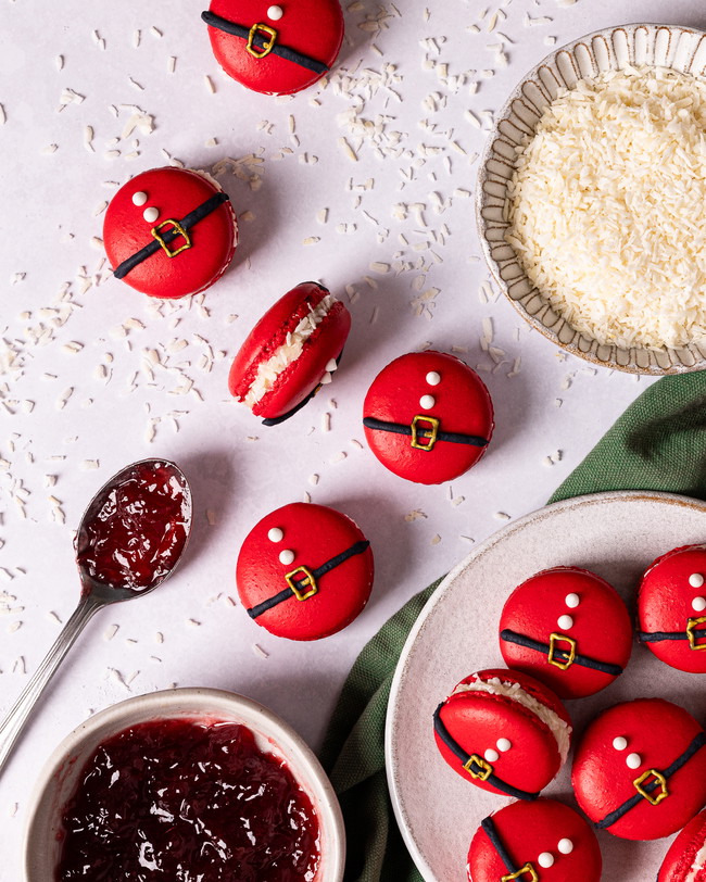 A pile of macarons decorated like a Santa outfit on a plate