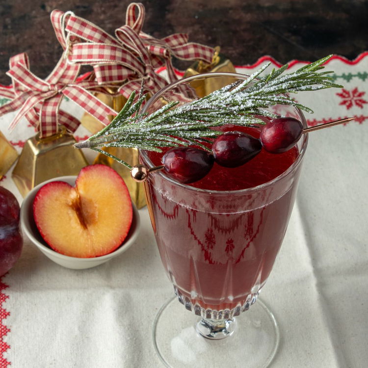 Image of Thread three cranberries onto a cocktail pick and lay across...