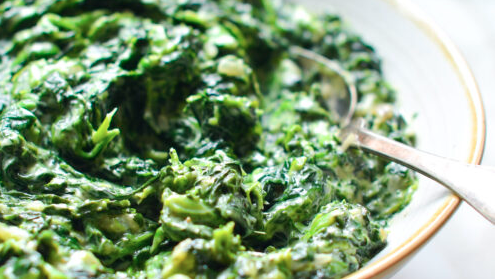 Creamy tamarind spinach served in a shallow bowl, featuring vibrant green cooked spinach folded into a rich, tangy cream sauce — Filipino-inspired creamed spinach side dish using tamarind jam.