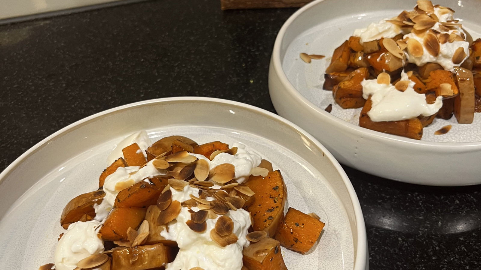 Wit serveerbord metv geroosterde pompoen, balsamico, Italiaanse kruiden, truffeloloe, burrata en geroosterde amandelschaafsel