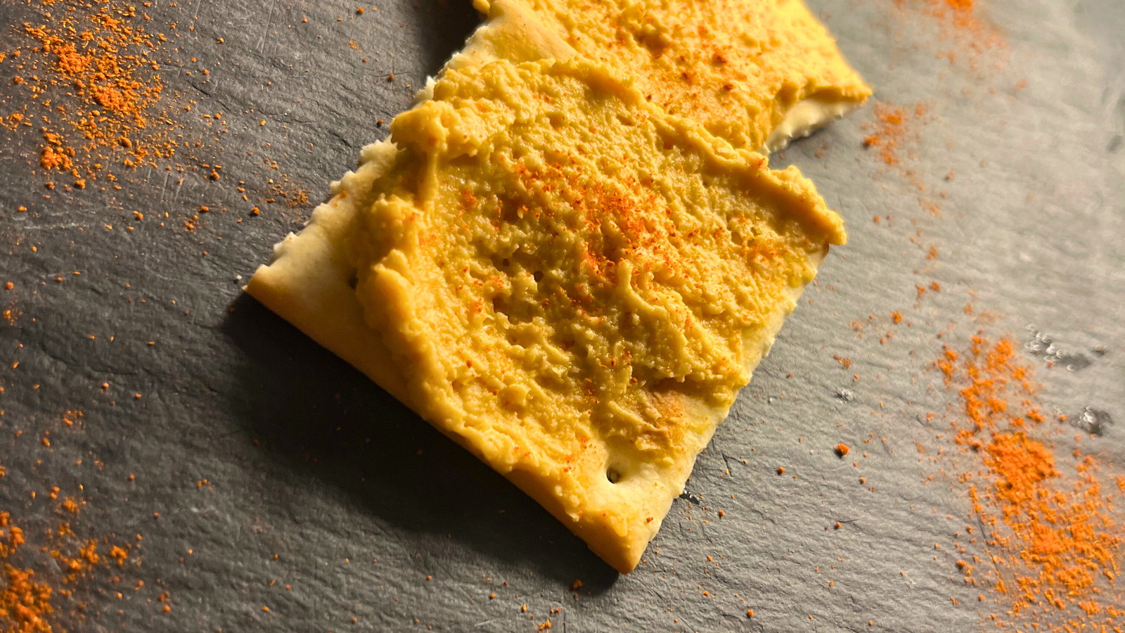 Serveer bord met toastjes besmeerd met hummus van paprika poeder, tomaat passata, kikkererwten, op een lijstenen bord 