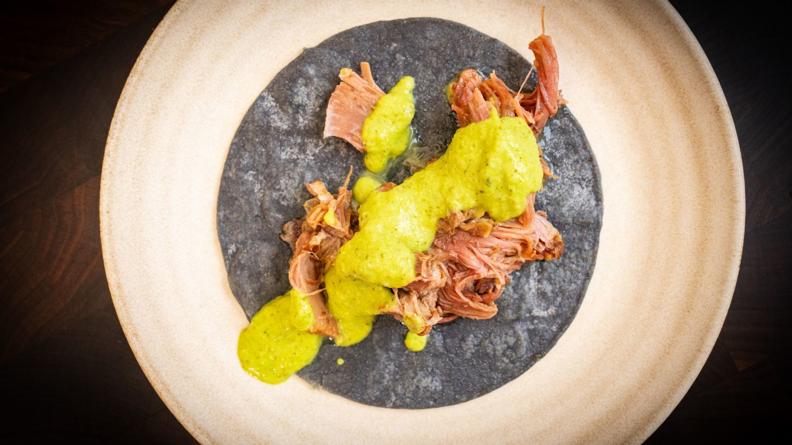 Carnitas taco topped with green salsa