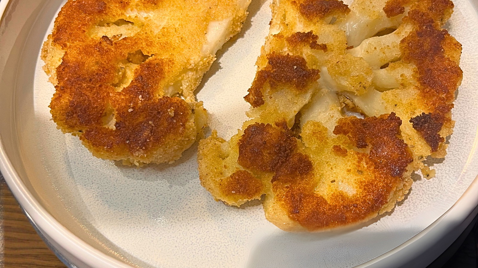 Serveerdbord op houten tafel met krokant gebakken bloemkool, vega snitzel