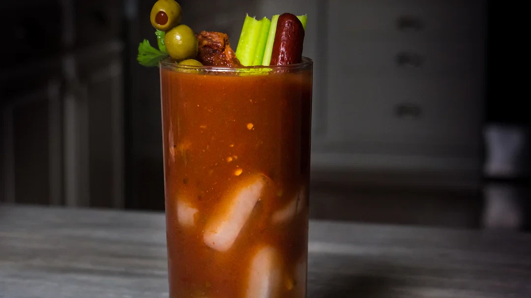 Spicy Bloody Mary cocktail garnished with olives, celery, and pepperoni stick, made with Carolina Reaper mash for extreme heat
