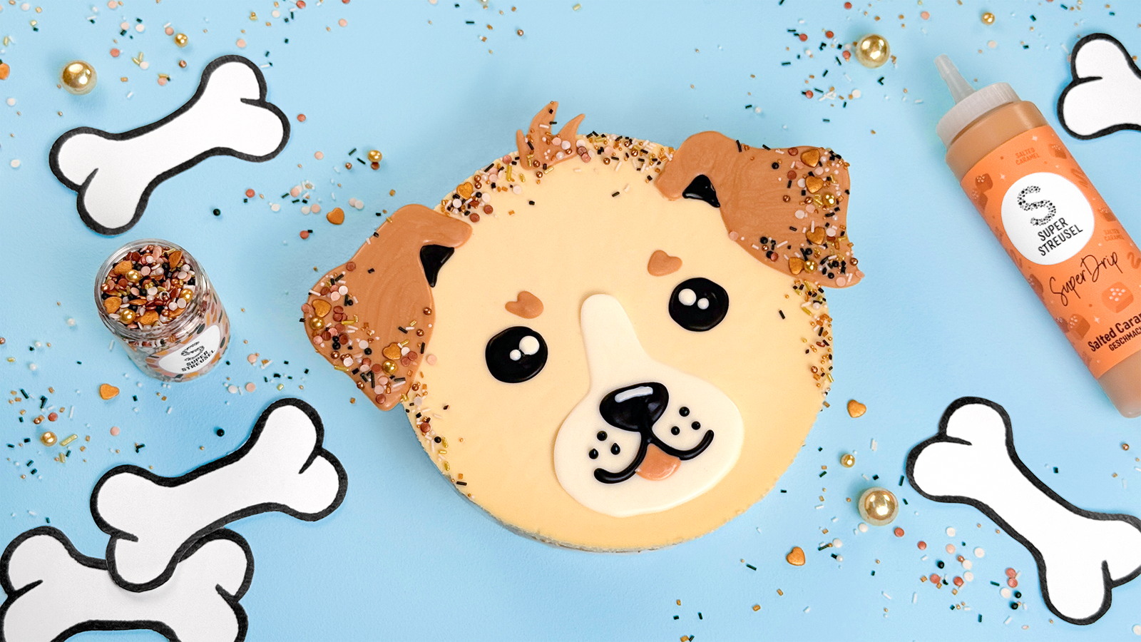 Hunde-Cheesecake mit karamellfarbenen Ohren und Fell aus Salted-Caramel-SuperDrip, dekoriert mit StreuselMix Casanova, schwarzen Augen und Nase aus SuperDrip sowie weißen Highlights. Niedlicher Cheesecake in Hundeoptik.