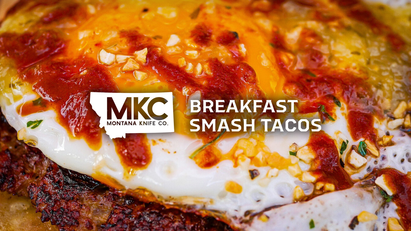 Close-up of a breakfast smash taco filled with sausage, eggs, bacon, and melted cheddar.