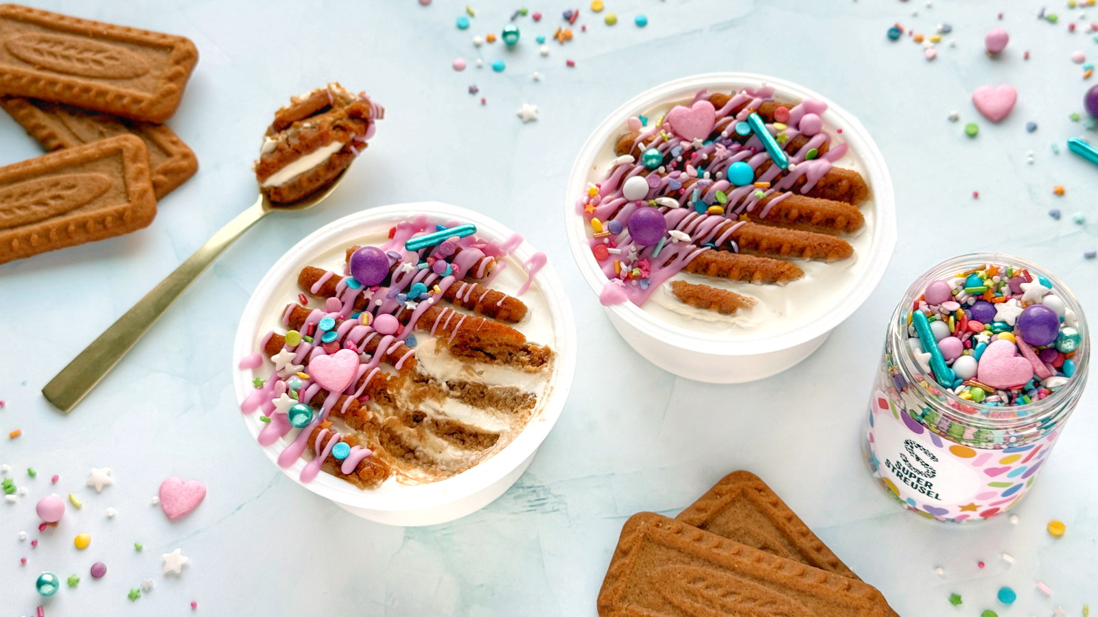 Viraler Joghurt Cheesecake im Becher aus griechischem Joghurt mit eingesteckten Karamellkeksen, dekoriert mit rosa SuperDrip und StreuselMix KonfettiParade. Schneller No-Bake-Dessert-Snack.