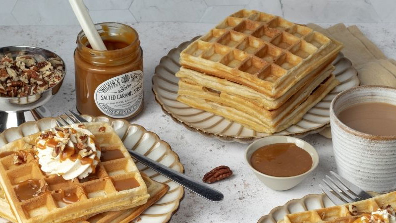 Plates of waffles with pecans and a jar of Tiptree Salted Caramel spread