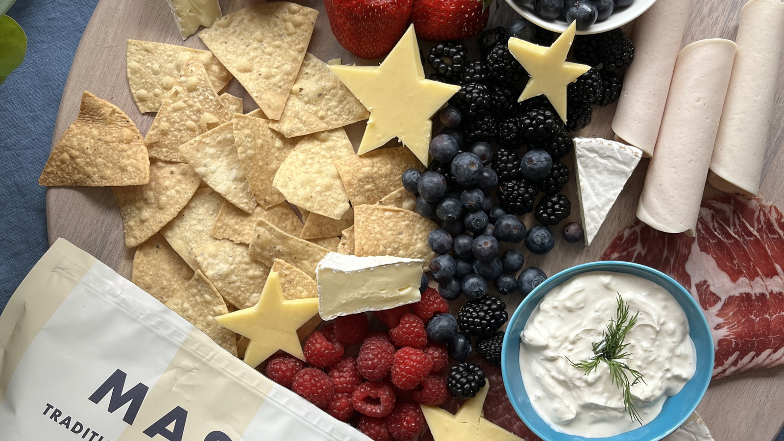 Ripe strawberries and blueberries, creamy brie, and savory ribbons of prosciutto and salami. Star-shaped cheese cutouts and a side of whipped herbed dip and MASA Chips.