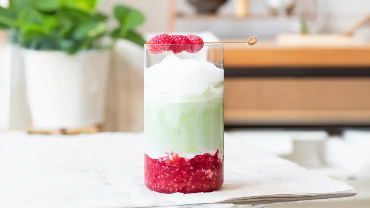 iced raspberry matcha latte with fresh raspberries and layered milk