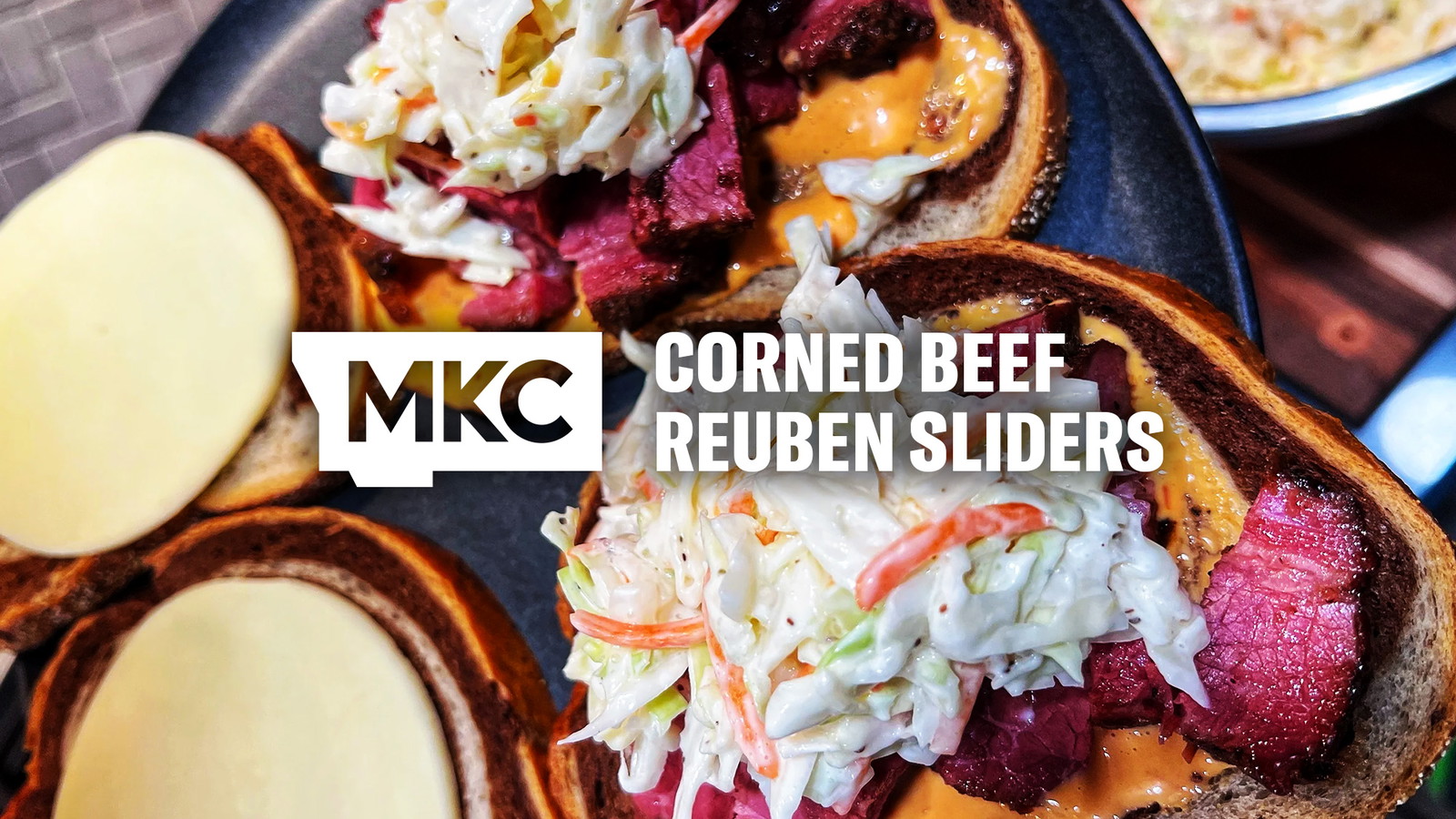 Corned beef Reuben sliders on toasted bread, topped with creamy coleslaw and sauce.