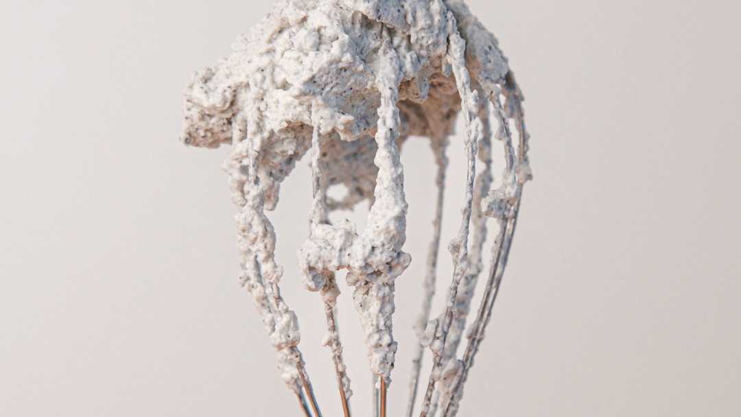 Speckled black sesame whipped cream on a whisk.