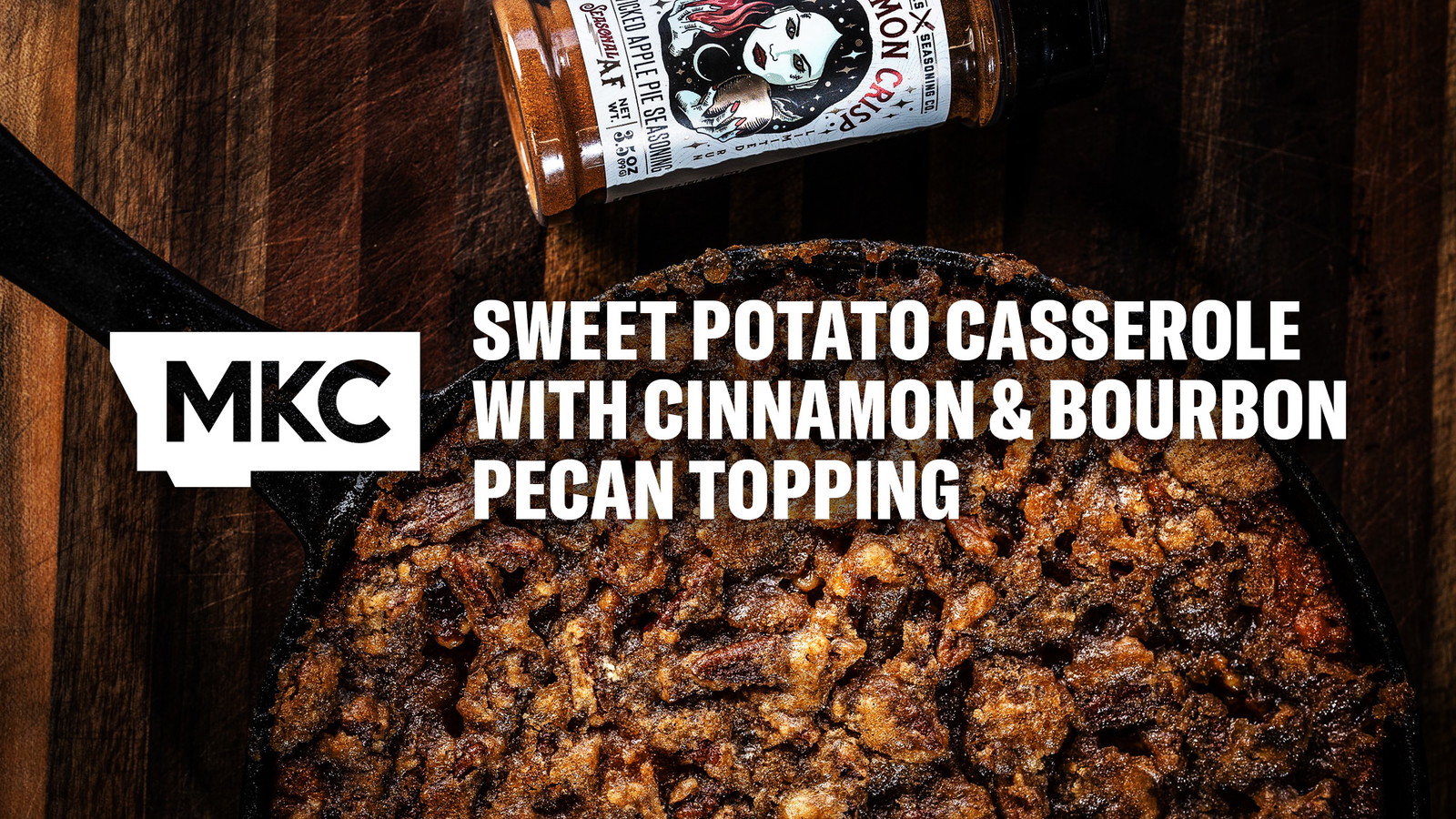 Golden sweet potato casserole with a crunchy cinnamon and bourbon pecan topping beside a bottle of Sinnamon Crisp seasoning.