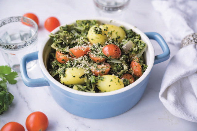 Stoofpotje van boerenkool met krielaardappelen, cherrytomaatjes en sesamzaadjes in een blauwe schaal