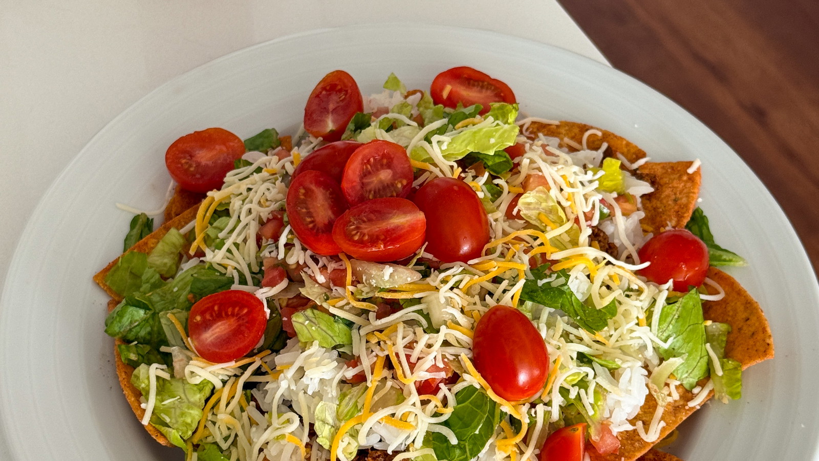A loaded fiesta platter featuring crunchy beef tallow MASA Chips topped with seasoned ground beef, warm rice, melted cheese, and fresh garden toppings.