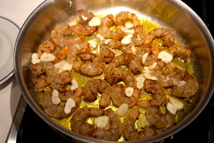 Image of Spread the thinly sliced garlic evenly over the shrimp.
