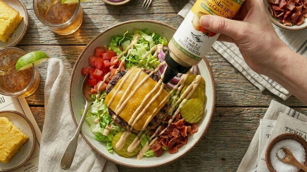 Image of Loaded Cheeseburger Bowl with Avo Everything Aioli Garnishing Squeeze