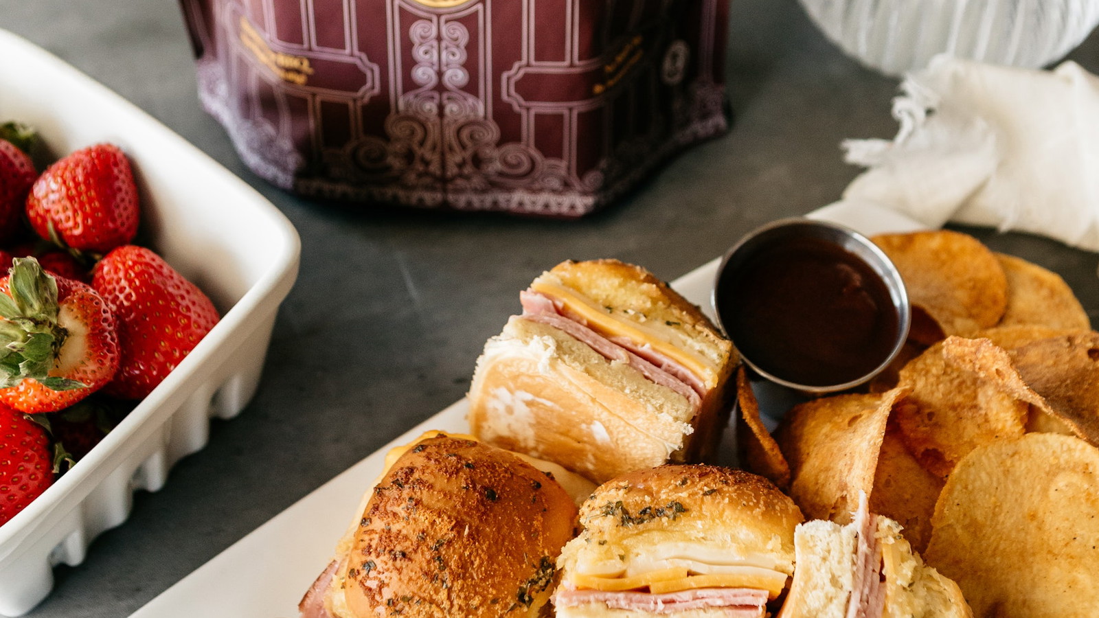 Warm, pull-apart ham and cheese sliders are brushed with a savory garlic butter and baked until melty served with Vandy Crisps