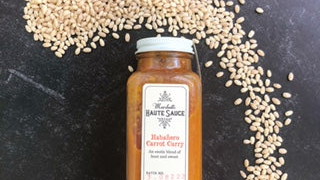 Bottle of Habanero Carrot Curry sauce with pearl barley grains